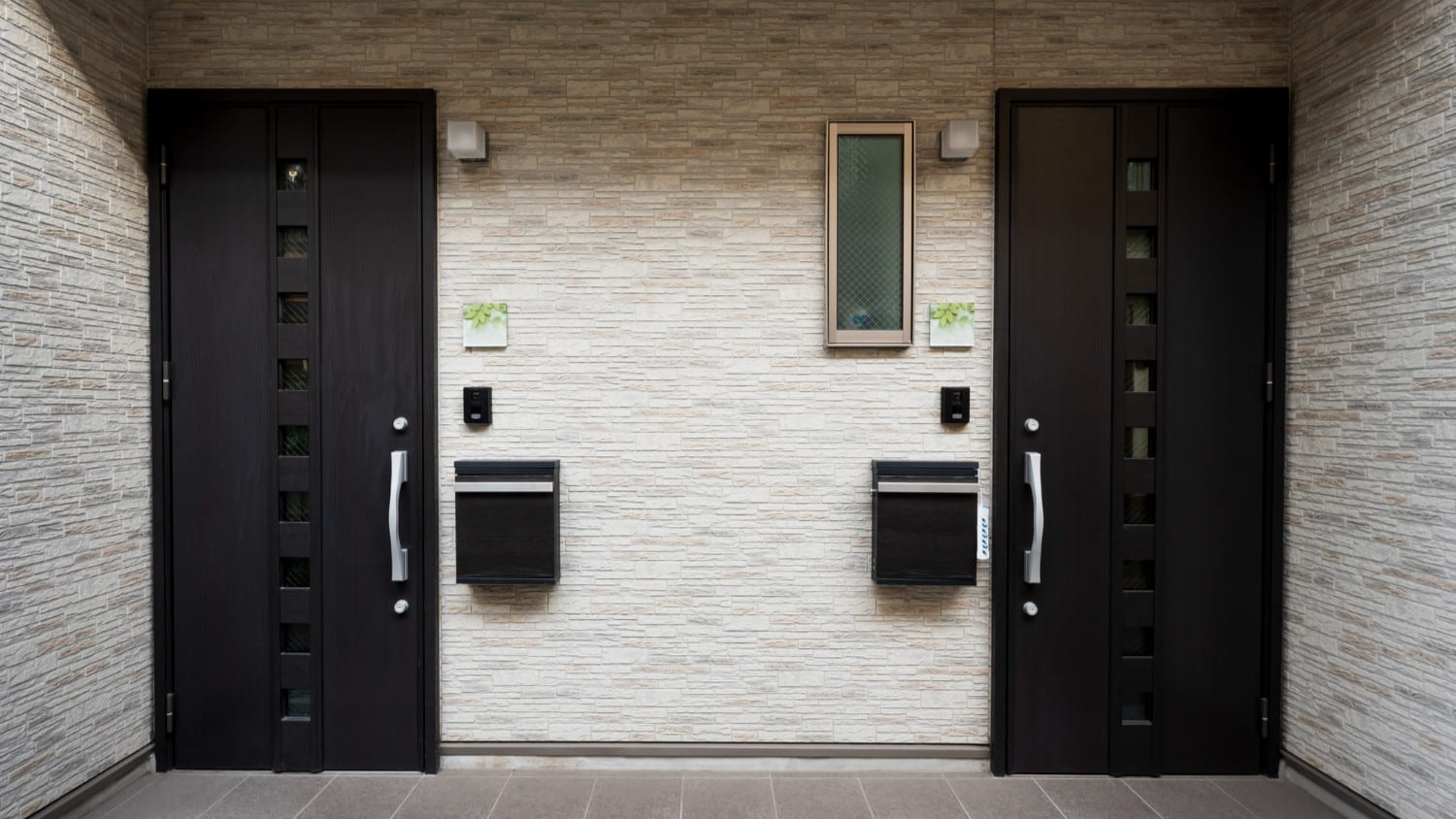 Twee moderne voordeuren met verticale glasstroken en moderne sloten in een strakke gevel