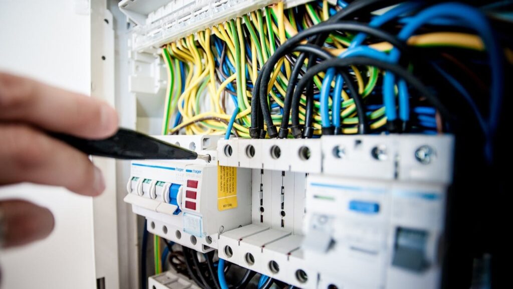 Elektricien voert controle uit aan meterkast vol gekleurde stroomkabels en schakelaars – elektricien tarieven 2025