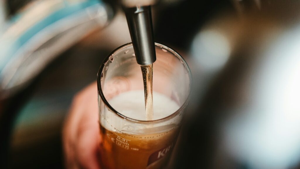 Zelf bier brouwen: versgetapt bier stroomt in een glas tijdens het brouwproces.
