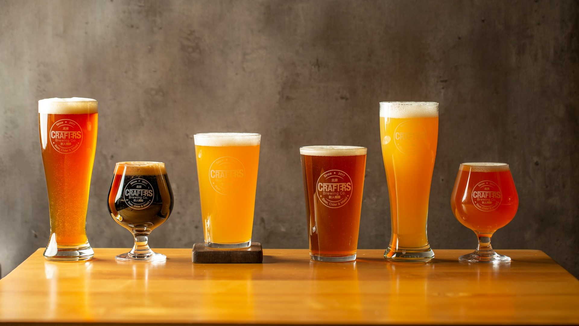 Zelf bier brouwen: zes soorten ambachtelijk bier in verschillende glazen op een houten tafel.