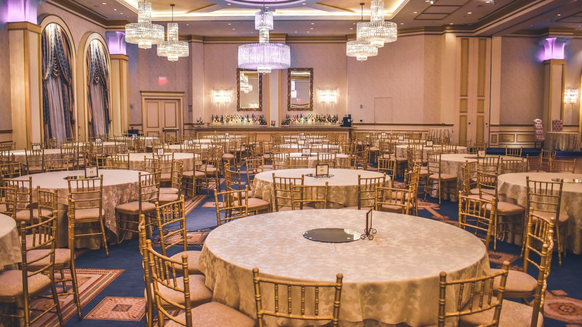 Luxe ingerichte zaal met ronde tafels en gouden stoelen voor een benefietavond organiseren