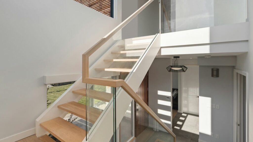 Moderne houten traprenovatie met glazen balustrade en strakke afwerking in een lichte woning