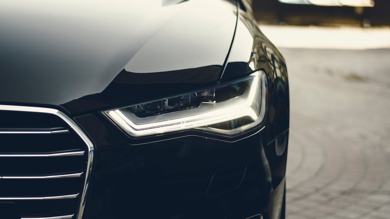 Close-up van de koplamp en grille van een luxe zwarte auto, ideaal voor zakelijk leasen