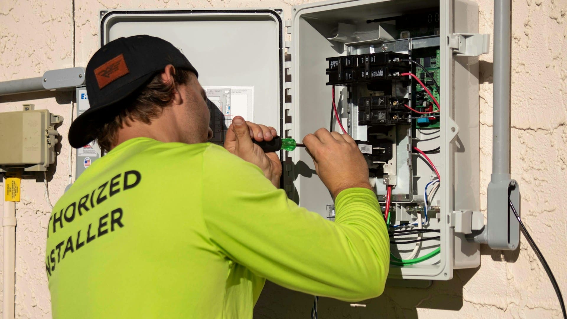 Elektricien vervangt groepenkast buitenshuis met schroevendraaier en gereedschap