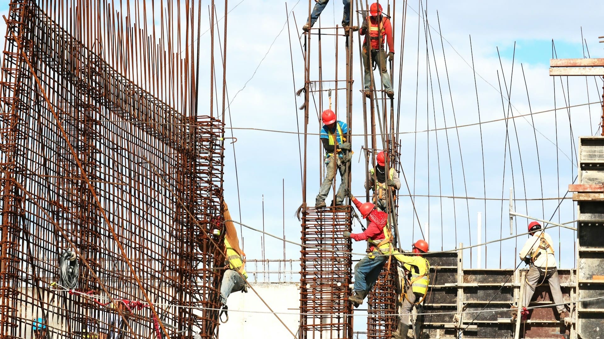 Bouwvakkers werken aan betonnen constructie, invloed op prijs per vierkante meter zichtbaar