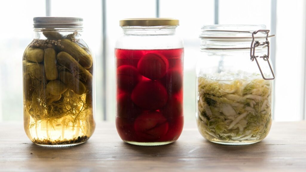 Glazen potten uit een fermentatieset met augurken, rode biet en gefermenteerde kool