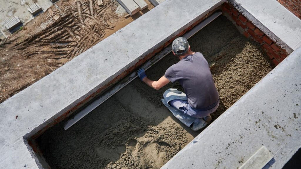 Aannemer egaliseert beton in een bekisting voor een betonnen fundering per m² tijdens bouwwerkzaamheden