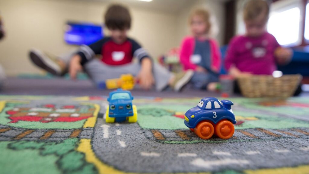 kinderopvang aan huis met peuters die spelen met speelgoedauto’s op speelkleed