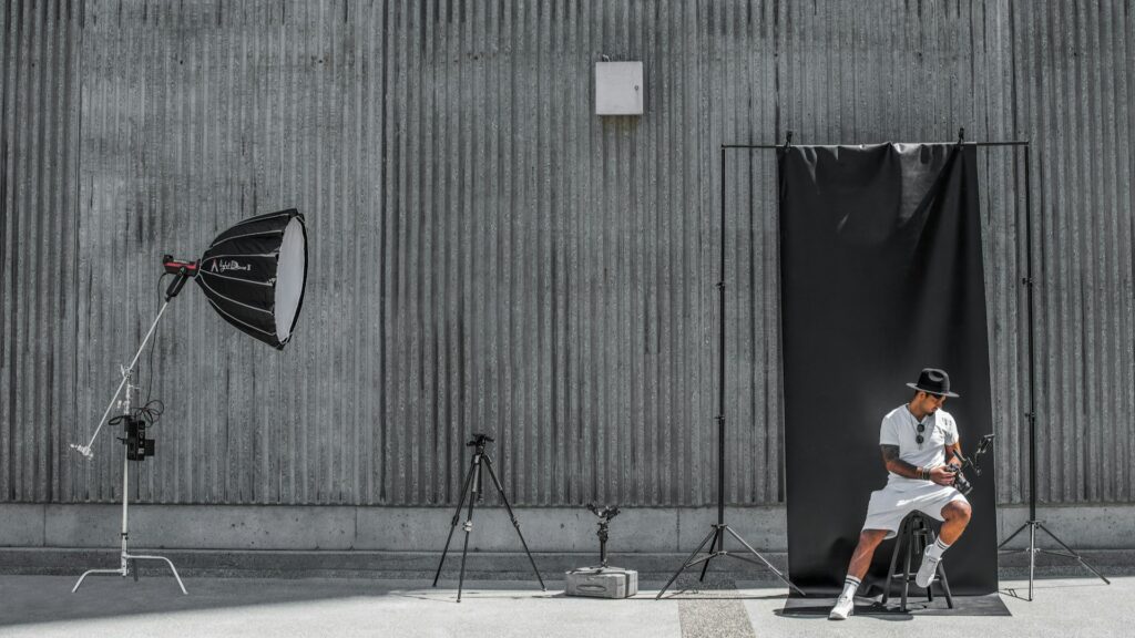 Modefotoshoot kosten zichtbaar in outdoor setup met model, lichtopstelling en zwarte backdrop tegen industriële muur