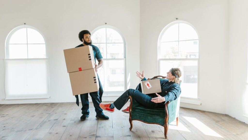 Man draagt dozen terwijl iemand zit in lege kamer bij kosten woningontruiming