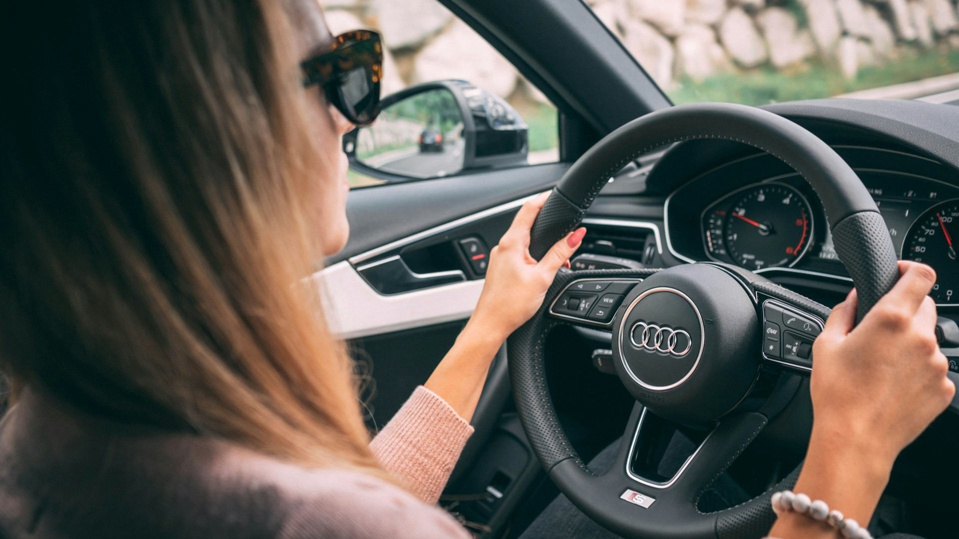 Jonge vrouw achter het stuur van een auto – de kosten van het eerste jaar autorijden als 18-jarige